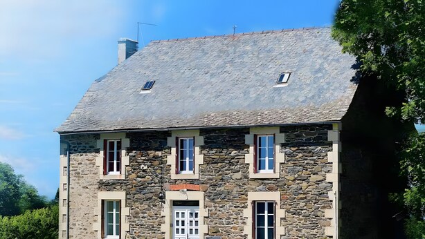 Una casa de piedra con una puerta central, dos ventanas a cada lado y un pequeño respiradero en el techo.