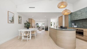 Una cocina moderna con una isla curvada, iluminación colgante y un ventanal grande.