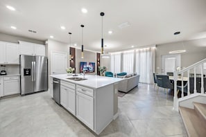 Experience a bright and spacious kitchen with a large island, sleek cabinetry, and modern pendant lights, perfect for casual meals. The open layout flows effortlessly into a cozy dining area, ideal for gatherings with loved ones. - 5BR townhouse at Windsor Cay Resort (Clermont)
