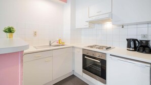 Een moderne keuken met witte kasten, een roestvrijstalen oven, een koffiezetapparaat en een spoelbak.