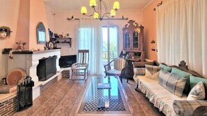 Un soggiorno con camino, divano, tavolino e lampadario.