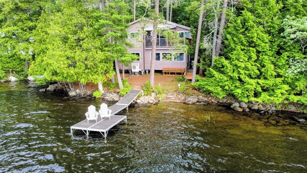 A cabin by a lake with a dock and chairs. - 3-Bedroom House on Beautiful Flying Pond in Mt. Vernon, ME (Mount Vernon)