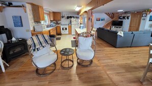 A modern kitchen with wooden cabinets, a dining area with a table and chairs, a gray sofa, and a small round table with two chairs. - 3-Bedroom House on Beautiful Flying Pond in Mt. Vernon, ME (Mount Vernon)