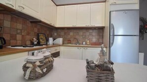 Una cocina con armarios blancos, un refrigerador de acero inoxidable y dos cestas de mimbre sobre la encimera.