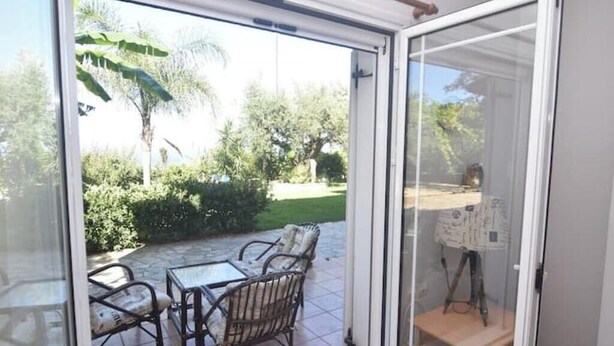 Un patio con puerta de cristal, mobiliario exterior y vistas al jardín.