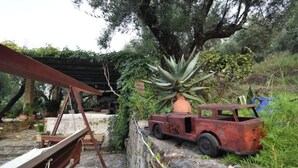 Un entorno rústico al aire libre con un coche antiguo, una hamaca y una planta de agave grande.