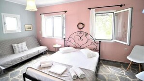 A bedroom with a bed, a sofa, a small table, and a chair. - Sweet Studio with Amazing Sea View (Zakynthos)