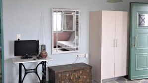 A room with a television, a mirror, a cabinet, and a green door. - Sweet Studio with Amazing Sea View (Zakynthos)