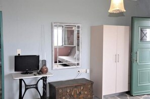 A room with a television, a mirror, a cabinet, and a green door. - Sweet Studio with Amazing Sea View (Zakynthos)