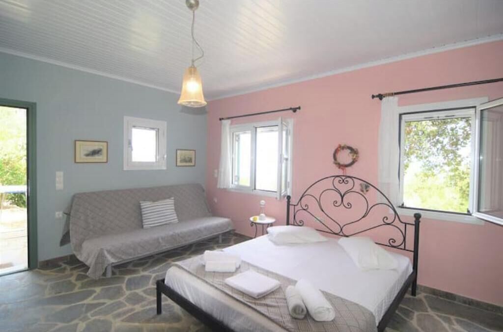 A bedroom with a bed, a sofa, a small table, and a window.