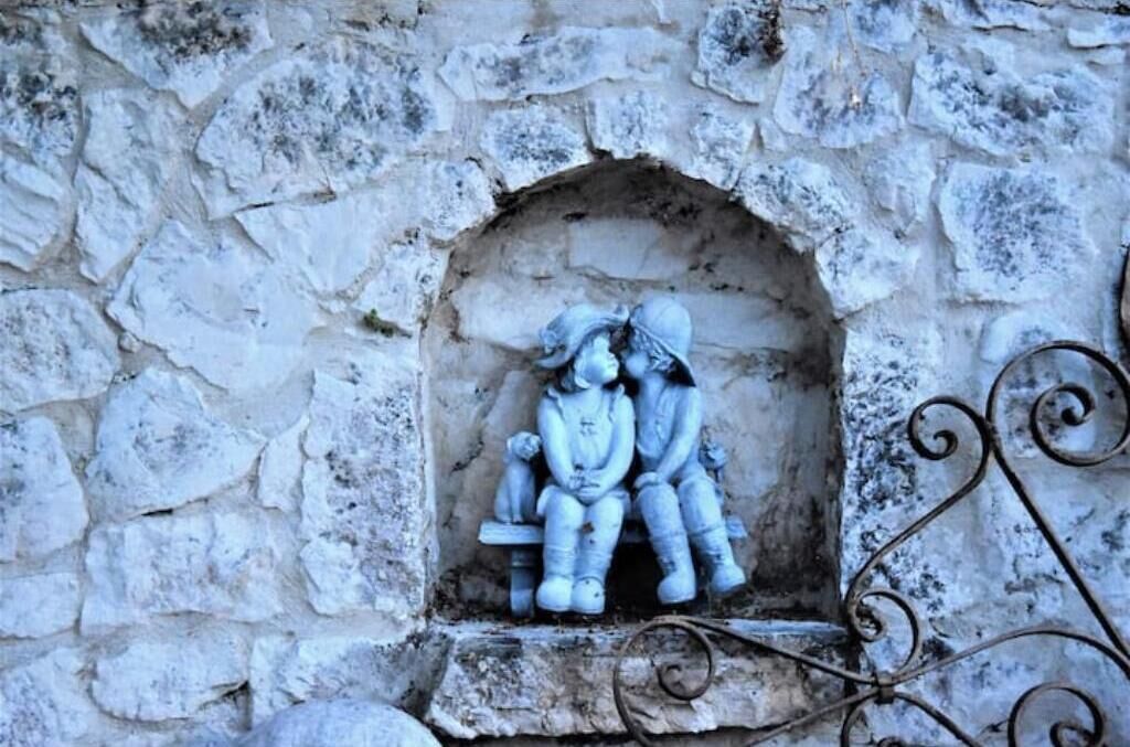 A stone wall with a small arched niche containing a sculpture of two figures.