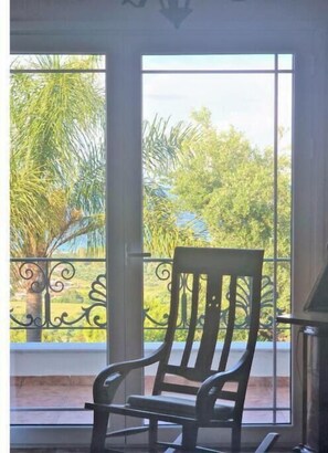 A room with a large window, a chair, and a decorative metal railing. - Alta Mare Villa - Up to 17 persons (Zakynthos)