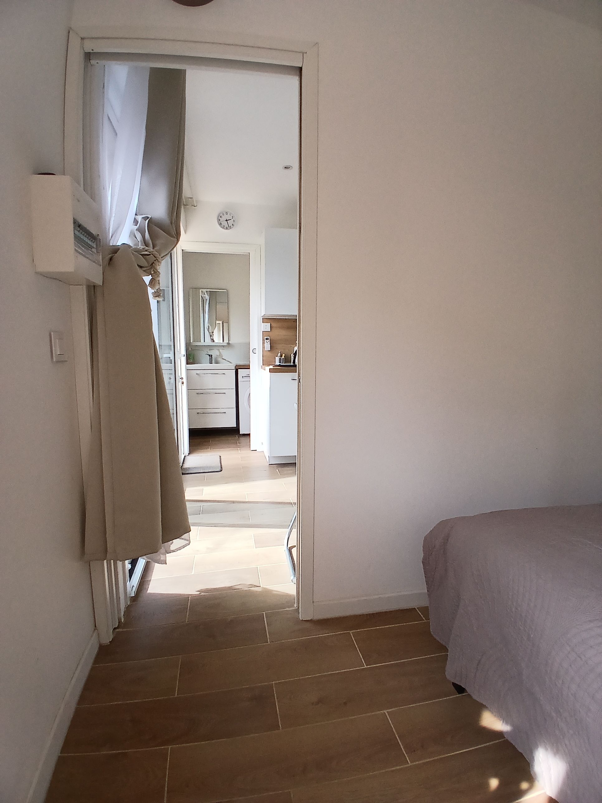 Un dormitorio con una cama, una puerta que da a un baño y vistas a una cocina.