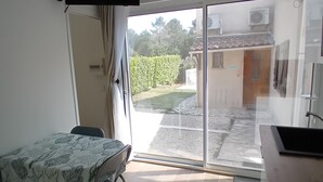 Una habitación con una mesa, sillas, un televisor y un ventanal corredero que da a un espacio exterior.
