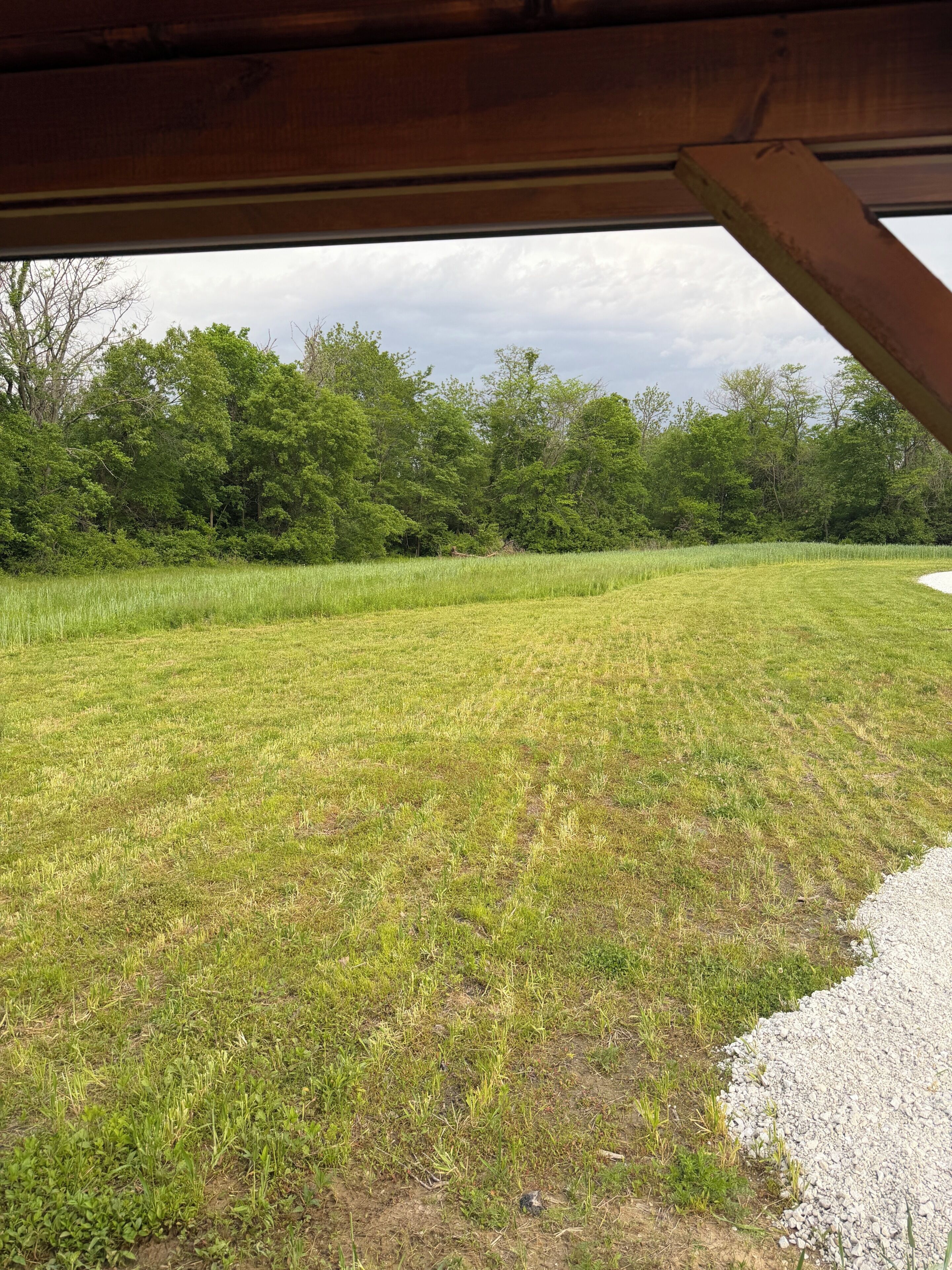 Un campo abierto con un camino de grava y una estructura de madera sobre él.