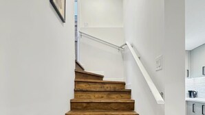 A wooden staircase with white walls and a kitchen area in the background. - Private Suite w/ Full Kitchen Near Banff National Park (Cochrane)