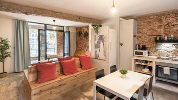 Un espacio de sala acogedor con un banco de madera, una mesa de comedor y una cocina con pared de ladrillo.