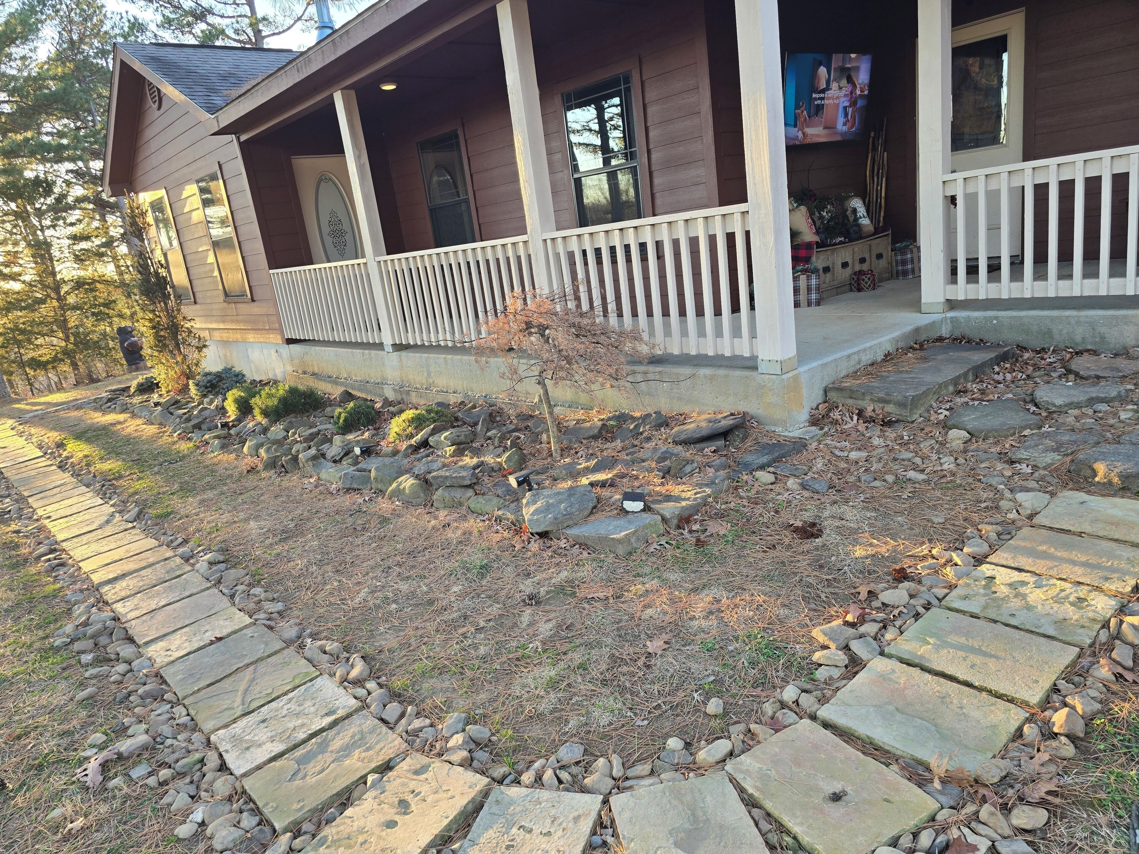 A house with a porch, stone pathway, and a small tree.