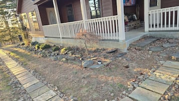 A house with a porch, stone pathway, and a small tree.
