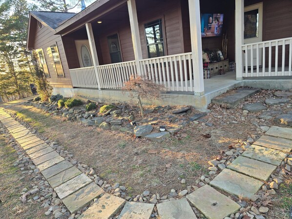 A house with a porch, stone pathway, and a small tree.