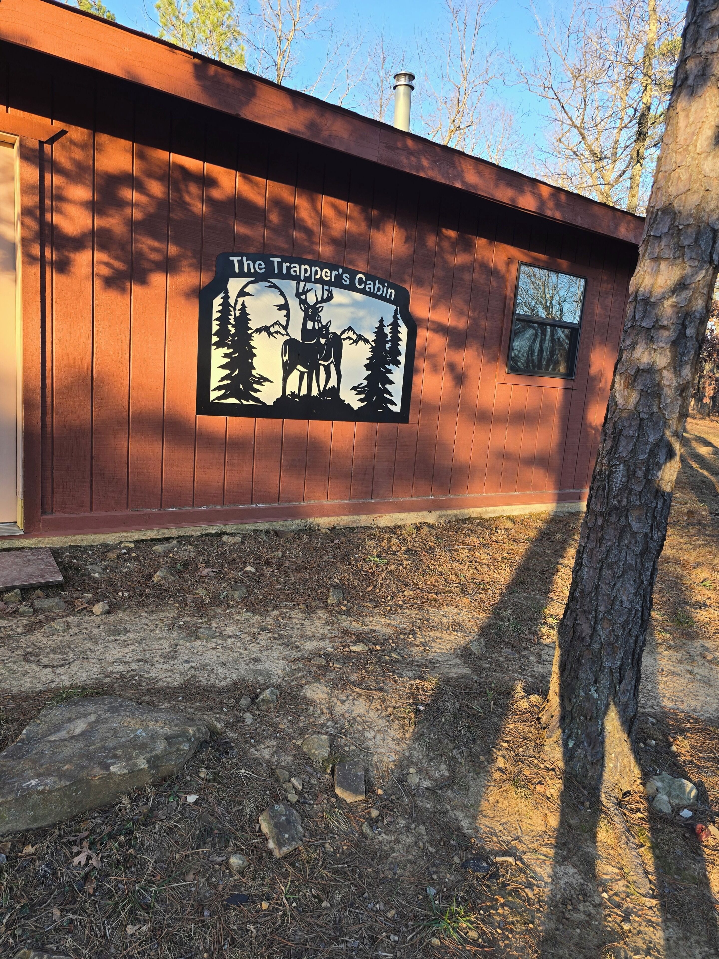 A cabin with a sign reading 'The Trapper's Cabin,' a window, and a wooden exterior.