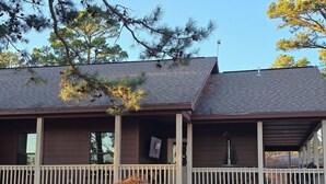 A two-story house with a covered porch, a chimney, and a small garden area with rocks and a tree.