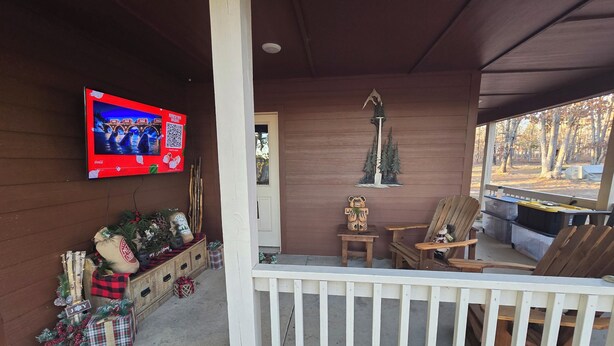 A porch with a television, Christmas decorations, a wooden bench, and a view of the outdoors.