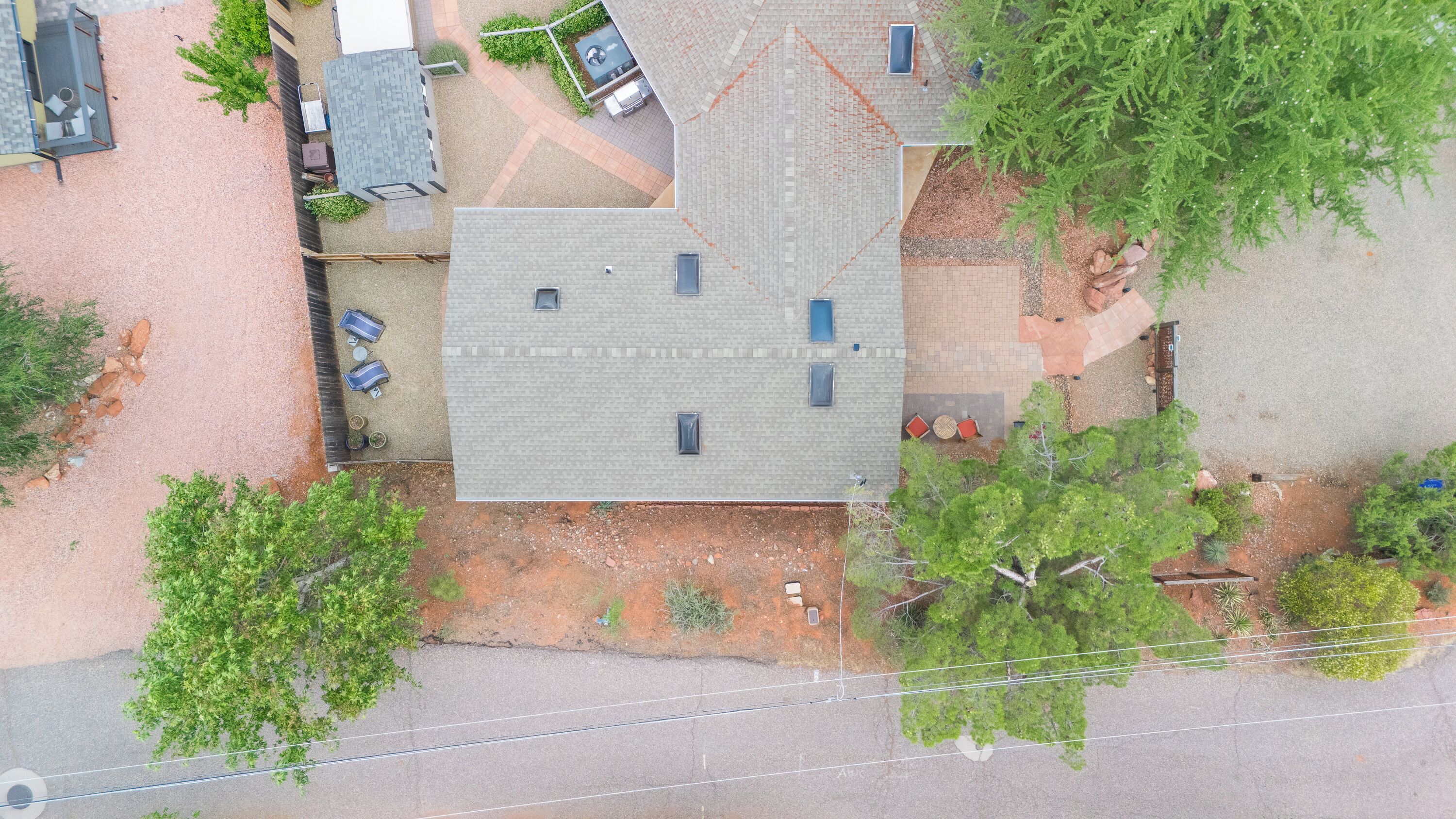 Vista aérea de una propiedad residencial con una casa de dos pisos, un camino de entrada y un pequeño jardín.
