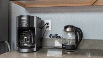 A coffee maker and a kettle on a countertop, connected to a power outlet.