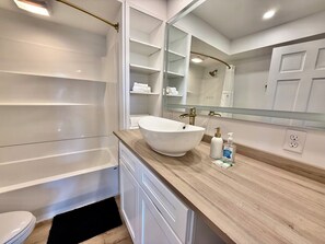 A modern bathroom with a freestanding bathtub, a large mirror, and a wooden vanity.