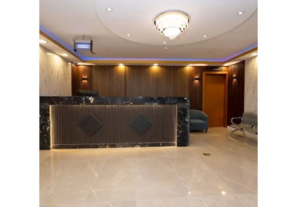 A reception area with a marble counter, a chandelier, and a wooden panel wall. - Wardat rahiq (Madinah)