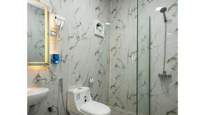 Baño con inodoro, lavamanos y ducha con mampara de vidrio.