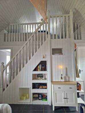 Eine Treppe mit weißen Geländern und einer weißen Wand, die Einbauschränke mit Büchern und dekorativen Gegenständen enthält.