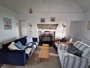 Ein Wohnzimmer mit Sofa, Ohrensessel, Couchtisch und Kamin.