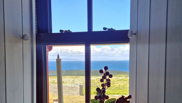 En flaske Aran Islands whisky og en vase med bær på et vindueskarm.