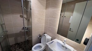 Un baño con cabina de ducha de vidrio, inodoro y lavamanos.