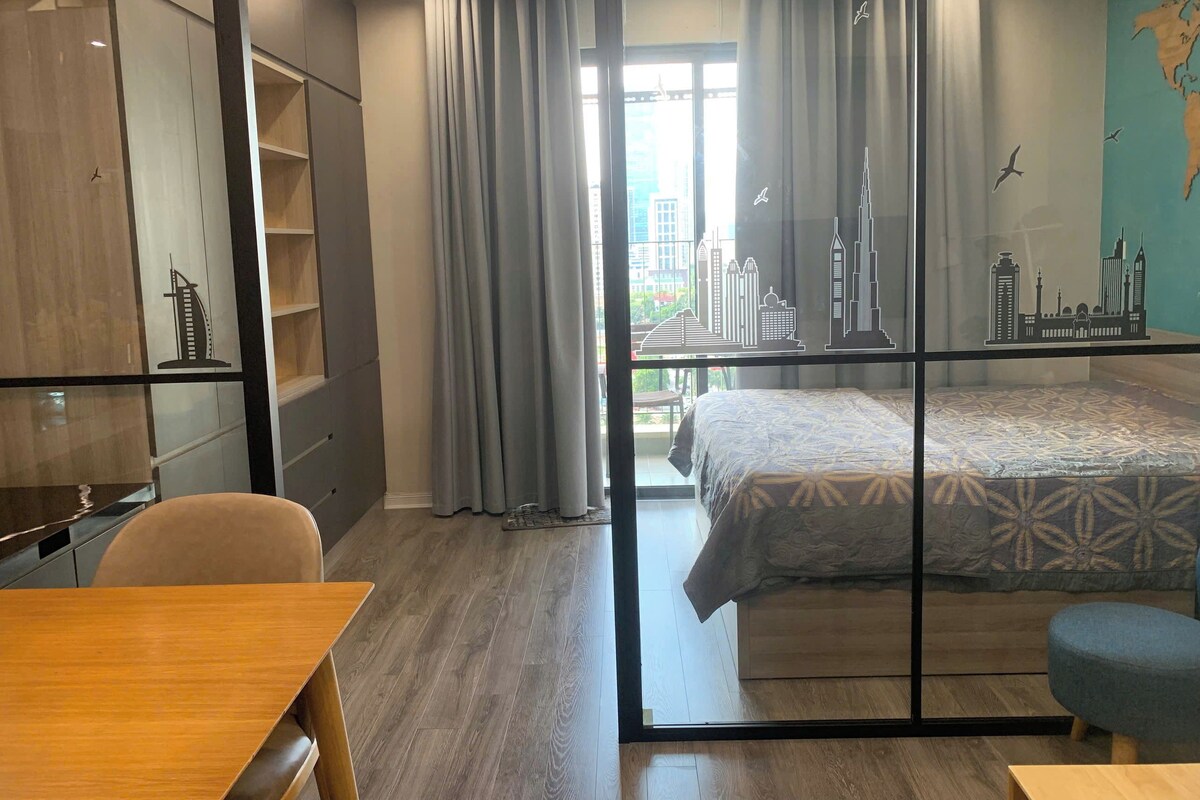 Een hotelkamer met een bed, een bureau, een stoel, een kledingkast en uitzicht op stadsgebouwen.