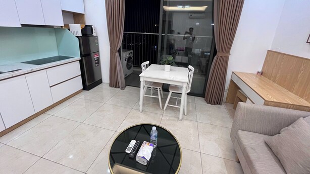 Una sala de estar moderna con una mesa de comedor, sofá y una zona de cocina con electrodomésticos.