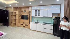 Una cocina moderna con electrodomésticos integrados, un televisor de pantalla plana y una persona usando un dispositivo móvil.