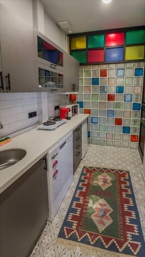 Una cocina con encimera blanca, lavamanos y salpicadero de colores.