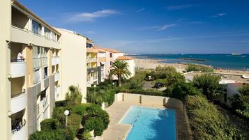 A hotel with a swimming pool, a beach view, and a multi-story building with balconies.