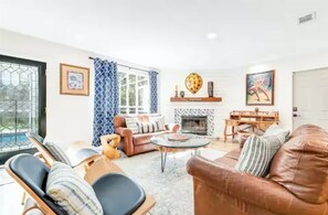 Una sala de estar con chimenea, un sofá, una mesa de centro y un comedor.