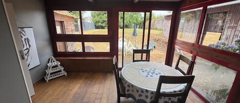A room with a wooden floor, a round table with chairs, large windows, and a skylight.