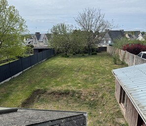 A residential backyard with a grassy lawn, a wooden shed, a metal fence, and a tree. - Just minutes from everything! Family townhouse close to all amenities (Bannalec)