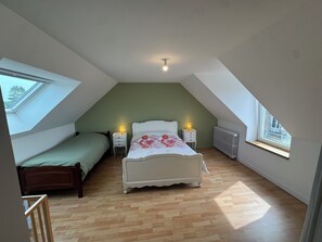A bedroom with a sloped ceiling, a large bed, two bedside tables with lamps, a radiator, and a window. - Just minutes from everything! Family townhouse close to all amenities (Bannalec)