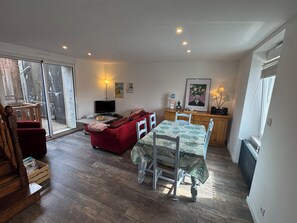 A cozy living room with a red sofa, a dining table with chairs, a TV, and a radiator. - Just a few minutes from everything! Family Townhouse Close to All Amenities (Bannalec)