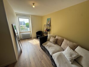 A room with a black sofa, a radiator, a window, and a bookshelf. - Just minutes from everything! Family townhouse close to all amenities (Bannalec)