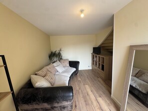 A living room with a sofa, a television on a stand, a bookshelf, and a staircase. - Just minutes from everything! Family townhouse close to all amenities (Bannalec)