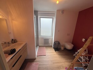 Ein kleines Badezimmer mit Dusche, Toilette und einem Holzkosmetikschrank.