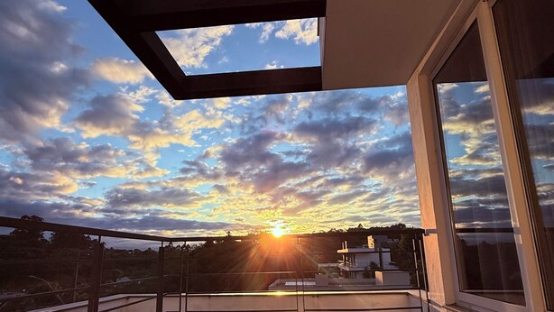 Moderni parveke, jolta avautuu esteetön näkymä auringonlaskuun ja kaupungin siluettiin.